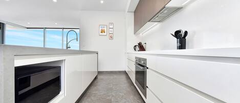 Una cocina moderna con horno empotrado, microondas y campana extractora de acero inoxidable.