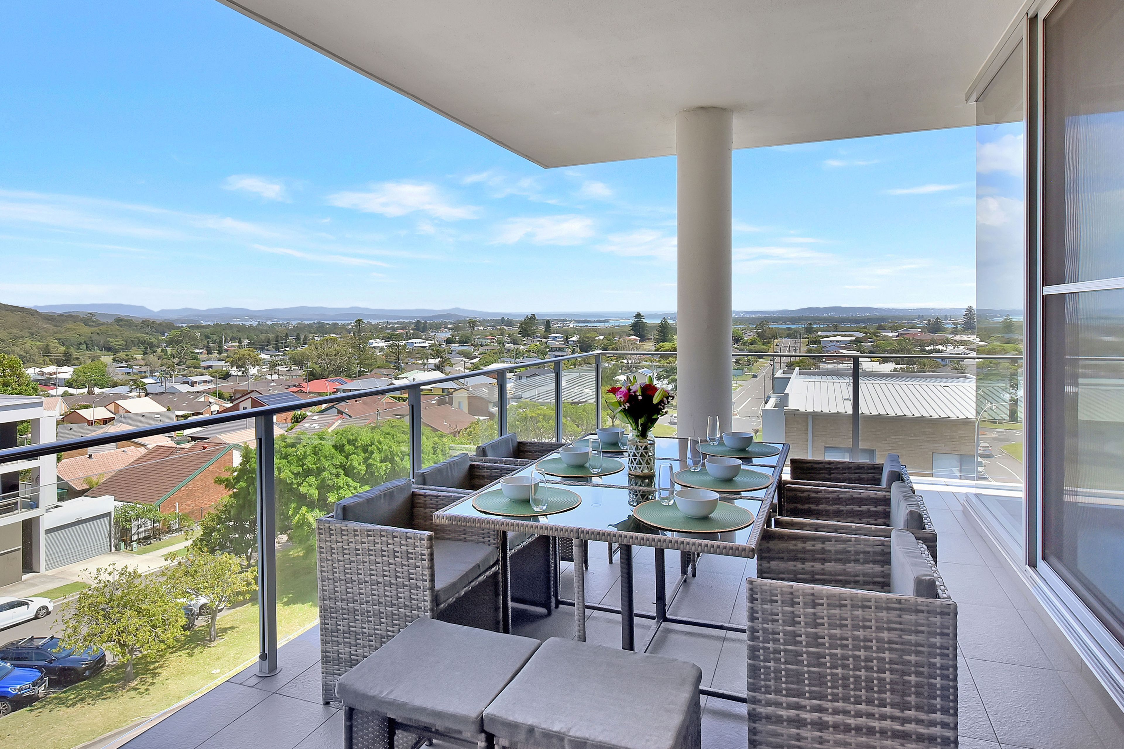 A balcony with a dining setup overlooking a residential area.