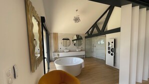 Un baño moderno con una bañera grande, una silla amarilla y una ducha a ras de suelo.