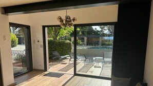 Una sala de estar moderna con un amplio ventanal corredero que da a un patio exterior.