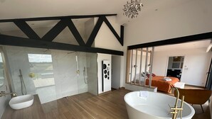 Un baño moderno con una bañera independiente, ducha con cerramiento de vidrio y tocador con lavamanos.