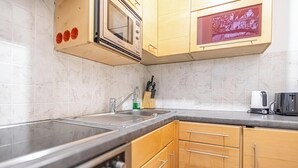 Una cocina con microondas, pileta y muebles de madera.