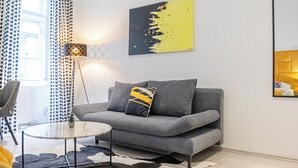 Una sala de estar moderna con un sofá gris, una mesa de centro redonda, una lámpara de pie y un tapete de cuero de vaca.