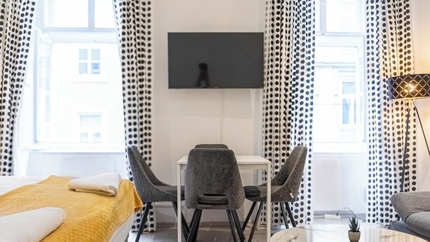 Una habitación de hotel con una cama, un escritorio con dos sillas, un televisor en la pared y un sofá.