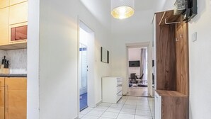 Un pasillo con una zona de cocina a la izquierda, un armario blanco y una puerta de madera a la derecha.