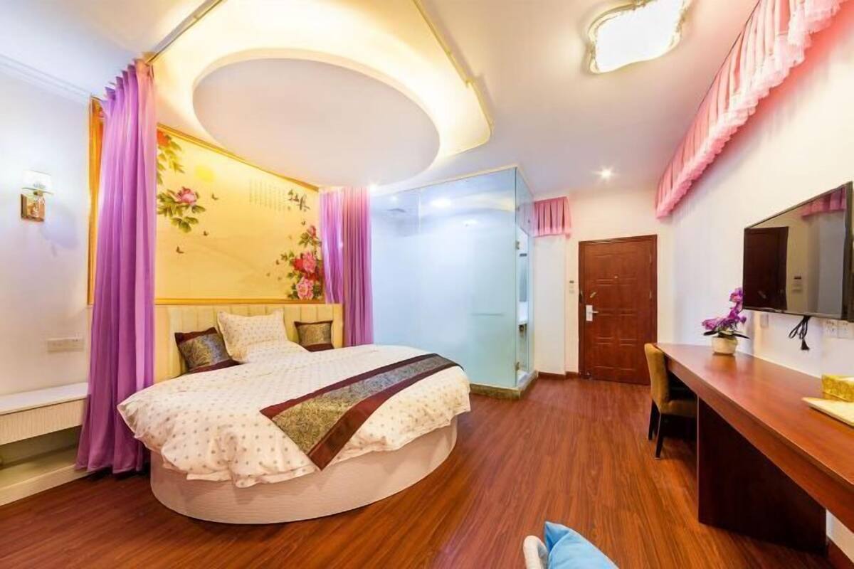 Une chambre à coucher avec un lit rond, un bureau et un miroir.