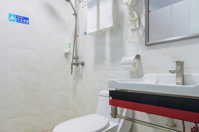 Un baño con inodoro, lavabo y ducha. Hay un letrero en la pared y un espejo sobre el lavabo.