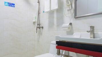 Un baño con inodoro, lavabo y ducha. Hay un letrero en la pared y un espejo sobre el lavabo.
