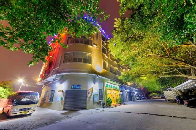 Un edificio de varios pisos con un espacio comercial en la planta baja, un área de estacionamiento y una calle arbolada.