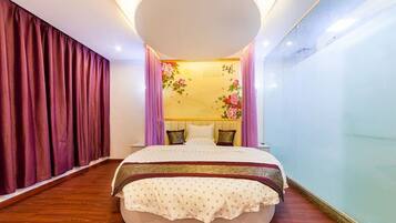 A bedroom with a large bed, a round ceiling light, and a wall with floral decorations.