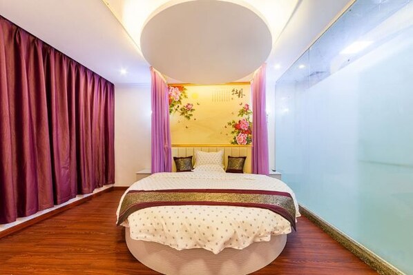 A bedroom with a large bed, a round ceiling light, and a wall with floral decorations. - Jiazhou Shishang apartment (Guangzhou Airport North Gate) (Guangzhou)