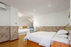 A hotel room with a large bed, a smaller bed, a desk with a computer, and a TV.