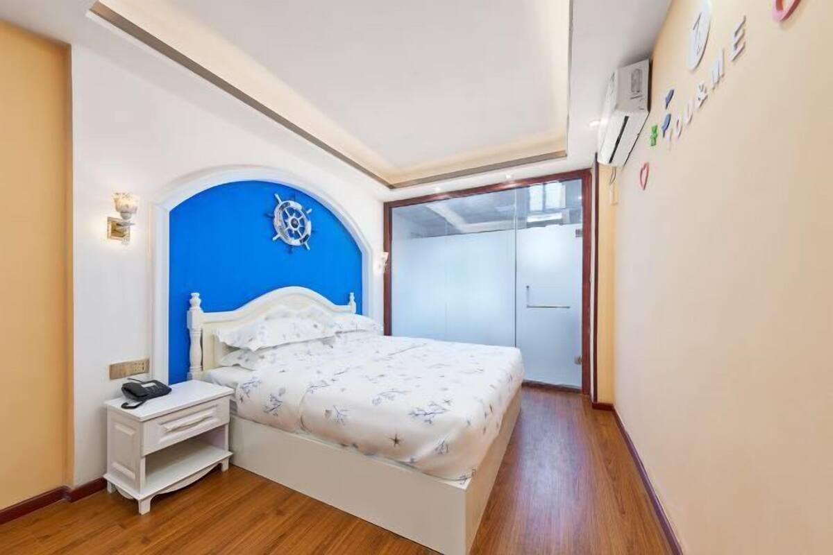 Une chambre à coucher avec un lit, une table de chevet et un mur d’accent bleu.