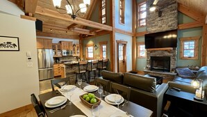 Una cocina amplia con electrodomésticos modernos, un comedor con una mesa grande dispuesta para seis personas, y una zona de estar acogedora con chimenea.