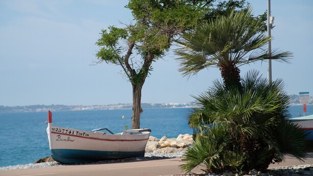 A boat named 'Bambino' docked near a tree and a street lamp by the seaside. - “Le Rose Garden” Apartment with Balcony, Wi-Fi, and Air Conditioning (Cagnes-sur-Mer)