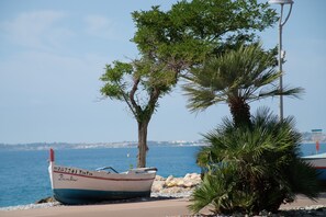 Ein Boot namens 'Bambino' liegt an einem Ufer an, in der Nähe eines Baumes und einer Straßenlaterne.