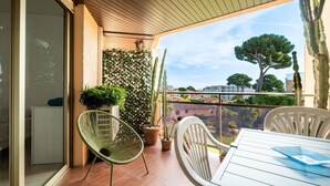 A balcony with a table, chairs, potted plants, and a view of the city. - “Le Rose Garden” Apartment with Balcony, Wi-Fi, and Air Conditioning (Cagnes-sur-Mer)