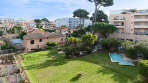 A residential area with a grassy yard, a swimming pool, and a large tree. - “Le Rose Garden” Apartment with Balcony, Wi-Fi, and Air Conditioning (Cagnes-sur-Mer)