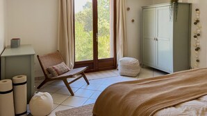 Ein Schlafzimmer mit Bett, Stuhl, Kleiderschrank und einem Fenster mit Vorhängen.