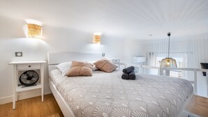 Ein Schlafzimmer mit Bett, Nachttischen, einem Ventilator und einer Hängelampe.