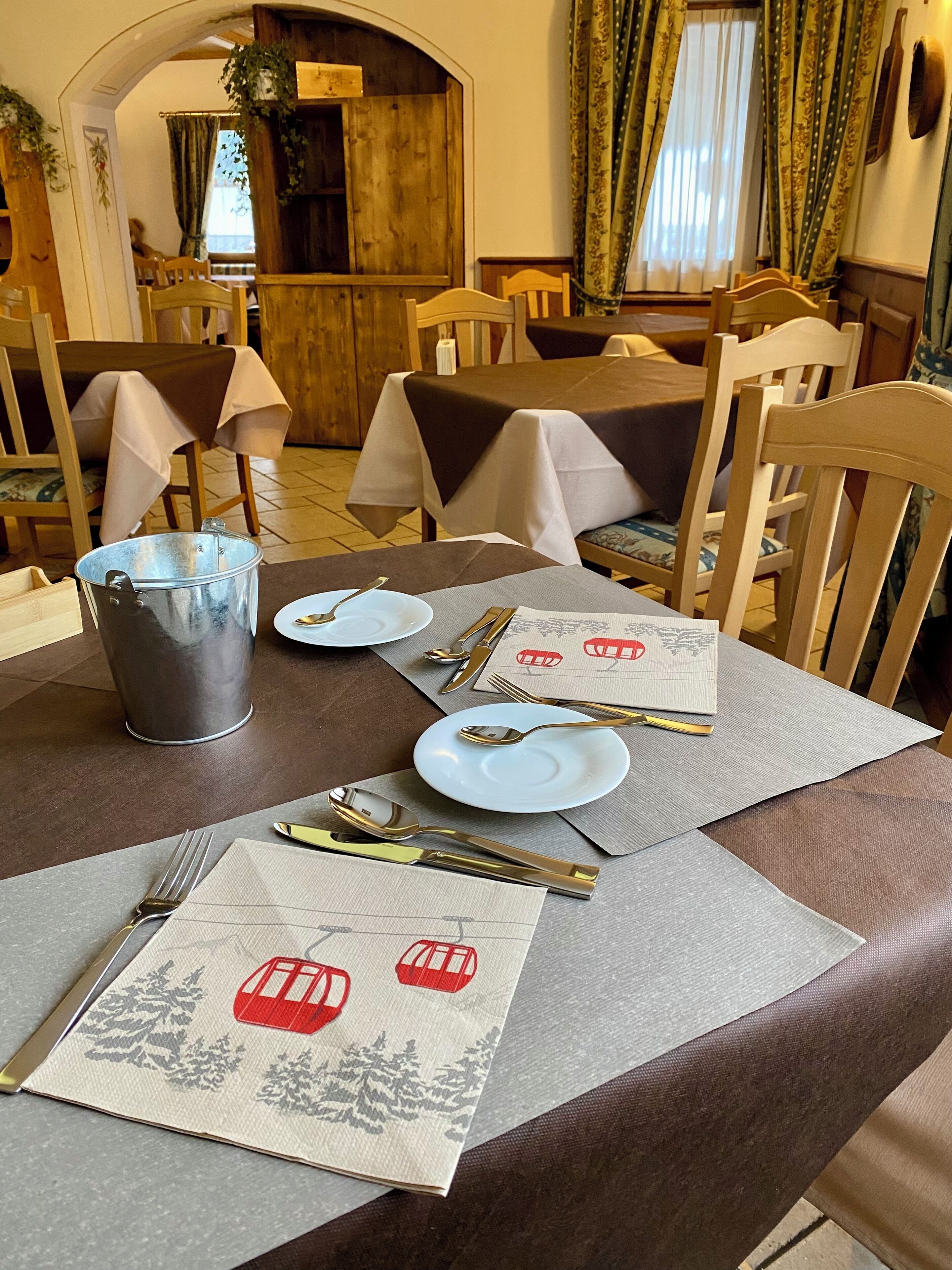 A dining table set with plates, cutlery, and napkins, with chairs around it.