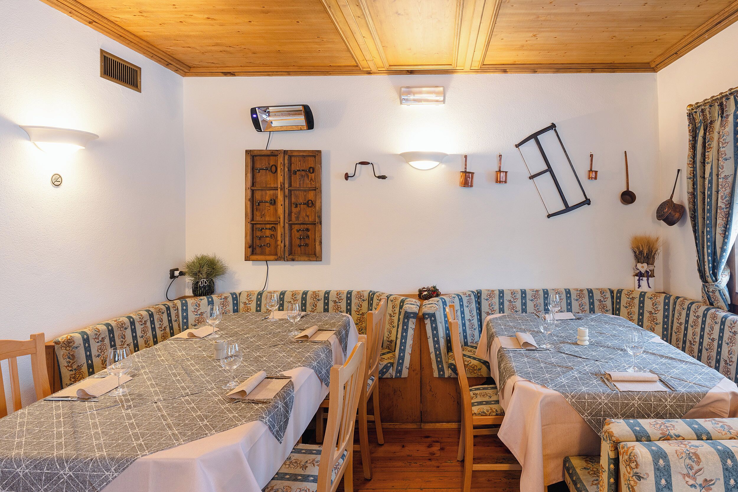 Un espace repas avec des tables et des chaises en bois, un ventilateur de plafond et des luminaires fixés au mur.
