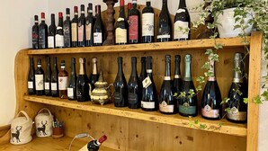 Un porte-bouteilles en bois contenant différentes bouteilles de vin et une théière décorative.