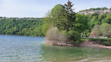 A lake with a forested shoreline and a distant rocky cliff.