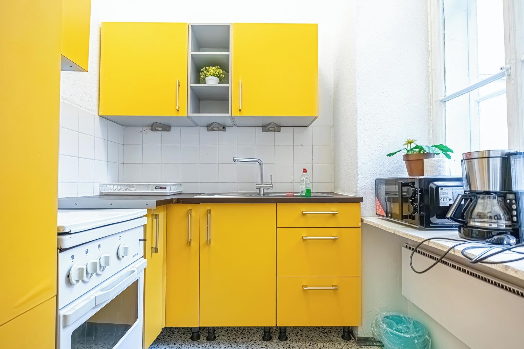 Una cocina pequeña con armarios amarillos, una estufa blanca y un microondas en la encimera.