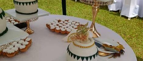 En bröllopsfest med ett bord uppdukat med tårtor i flera våningar, muffins och en tårtdekoration.