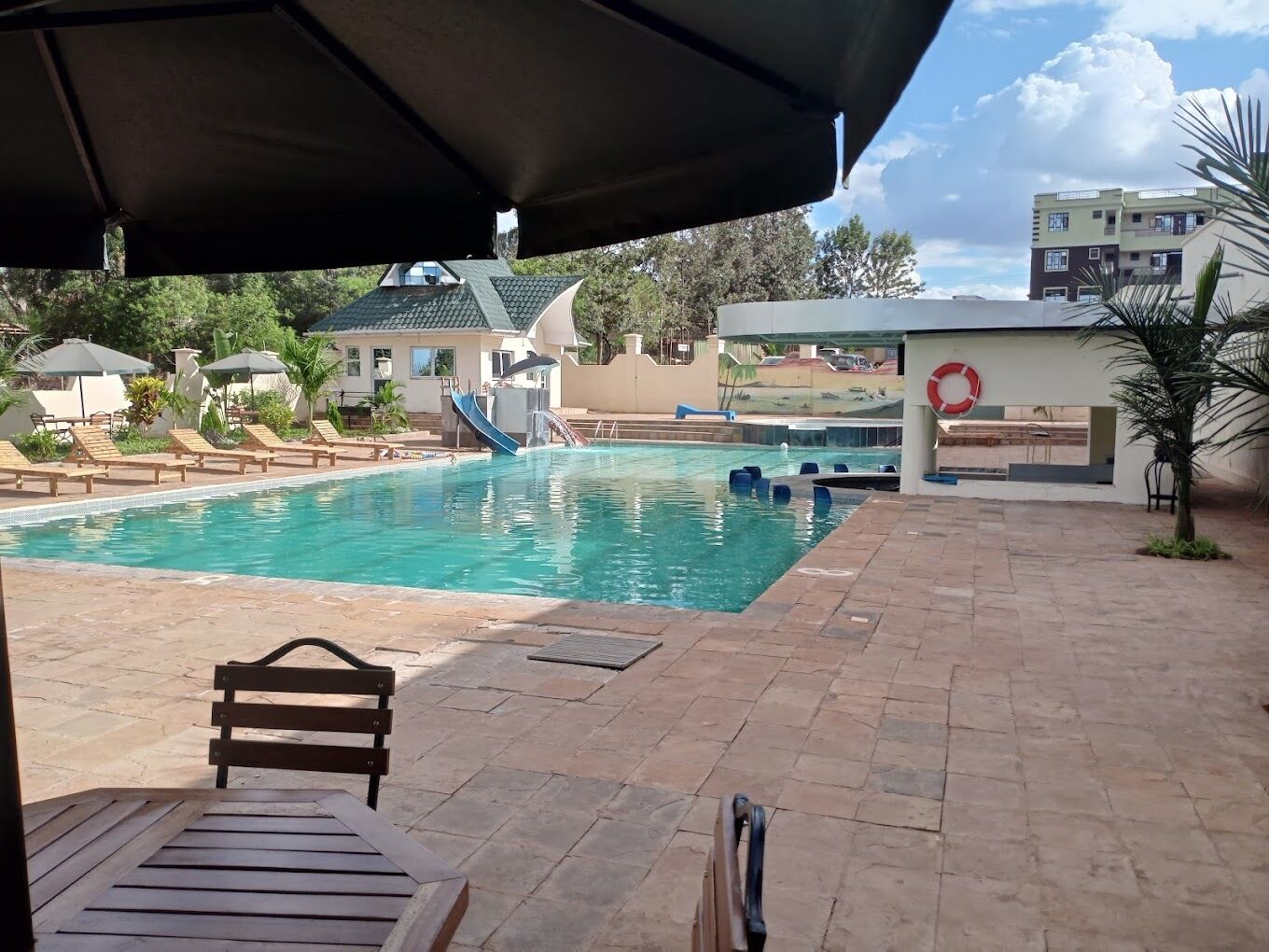 A pool area with lounge chairs and a lifebuoy on the wall.