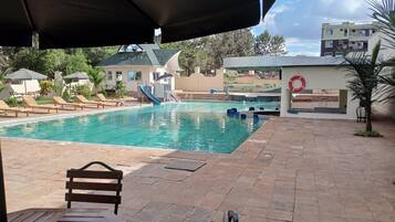 A pool area with lounge chairs and a lifebuoy on the wall.