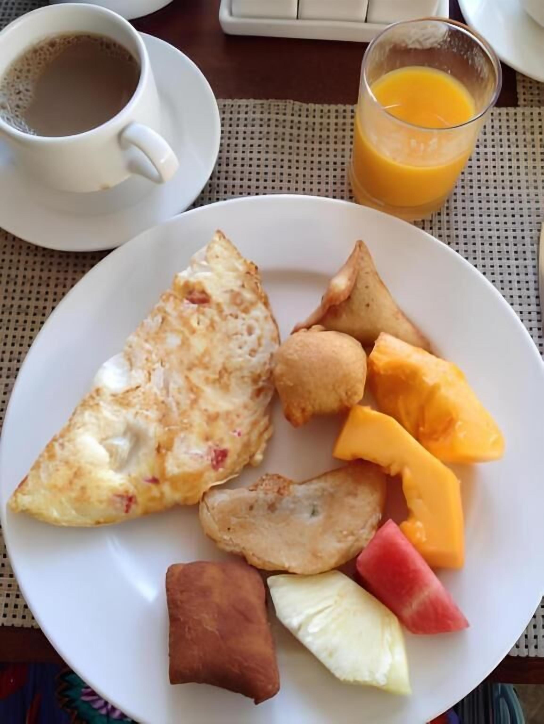 Un plato de desayuno con tortilla, patatas ralladas, una loncha de queso y fruta.