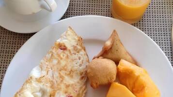 Un plato de desayuno con tortilla, patatas ralladas, una loncha de queso y fruta.