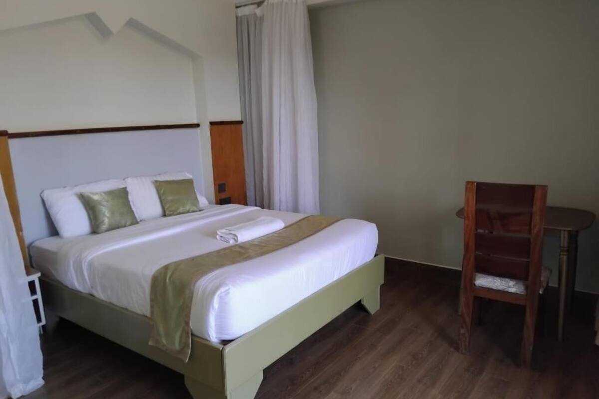 A hotel room with a bed, a chair, and a small table.