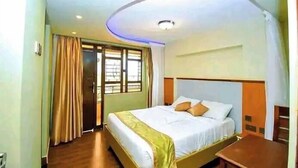 Ein Hotelzimmer mit Bett, Vorhängen, einem Fenster und einer Deckenleuchte.