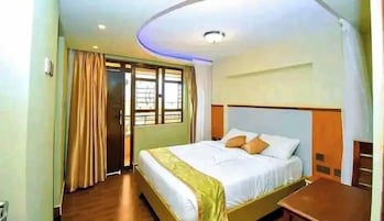 Una habitación de hotel con cama, cortinas, ventana y una lámpara en el techo.