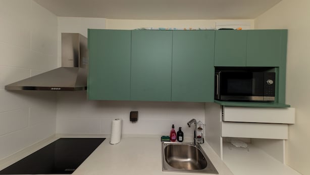 Una cocina moderna con estufa integrada, pileta de acero inoxidable y microondas.