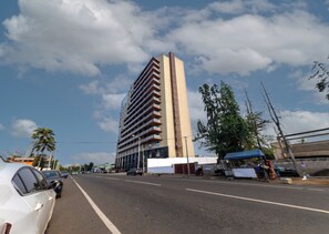 Ein hohes Gebäude mit mehreren Balkonen, einem klaren Himmel und einer Straße mit geparkten Autos.