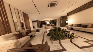 Un vestíbulo moderno con un mostrador de recepción, sofás y una decoración floral central.