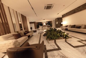 Eine moderne Lobby mit Empfangstresen, Sofas und einer zentralen Pflanzengestaltung.