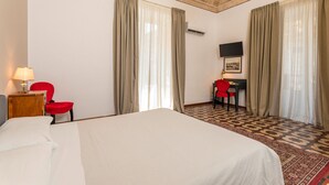 Ein Hotelzimmer mit Bett, Schreibtisch, Stuhl, Fernseher und Vorhängen.