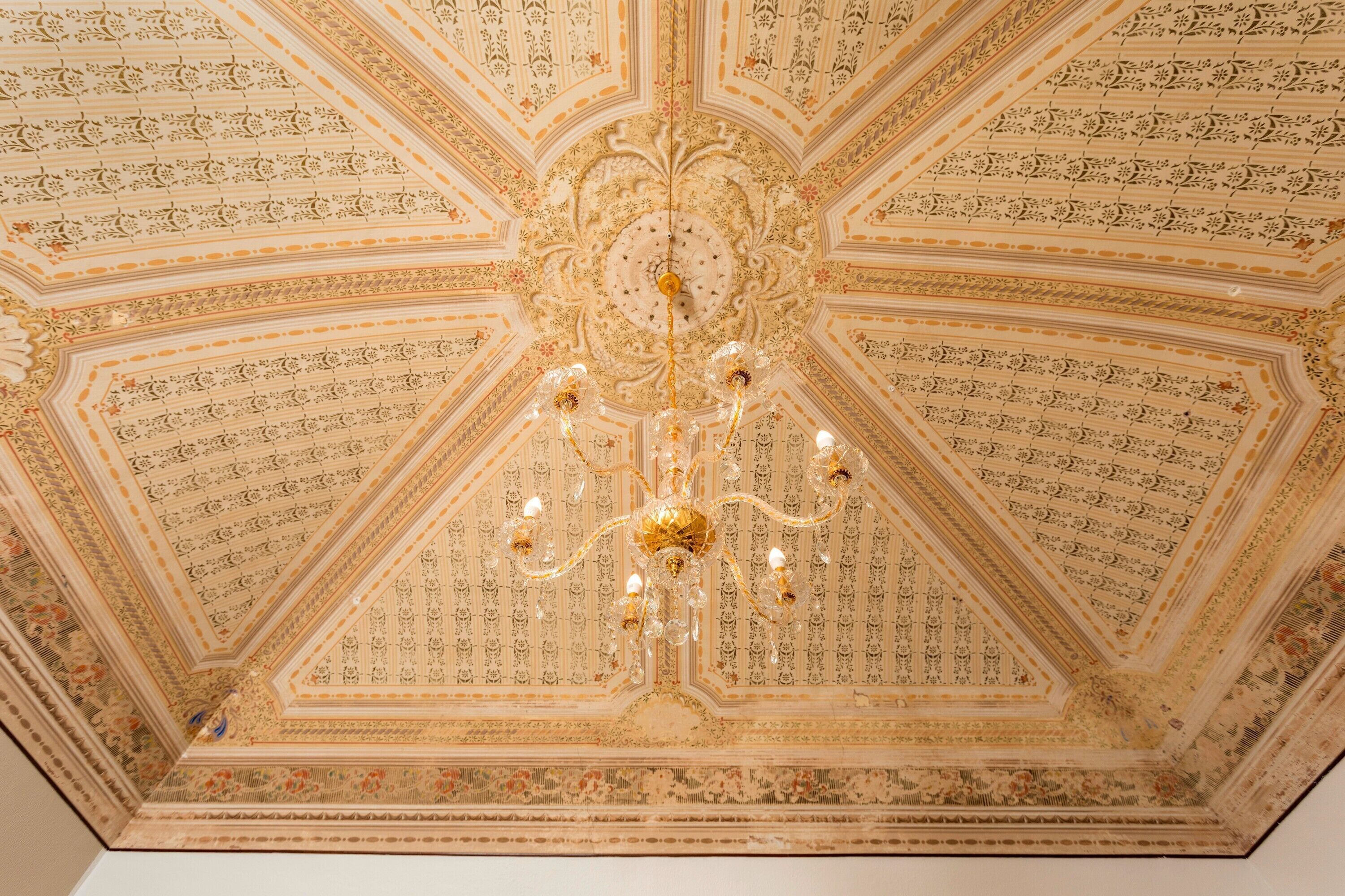 Een plafond met gedetailleerde bloemenmotieven en een centrale kroonluchter.