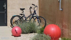 A bicycle parked against a wall, a red exercise ball, and a red exercise ball on a gravel surface. - Jezera Island Hideaway in Adriatic Sea (Tisno)