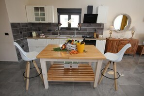 A modern kitchen with white cabinets, a wooden table, and two white chairs. - Jezera Island Hideaway in Adriatic Sea (Tisno)