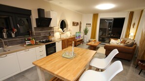 A modern kitchen with white cabinets, a wooden dining table, and two white chairs. - Jezera Island Hideaway in Adriatic Sea (Tisno)