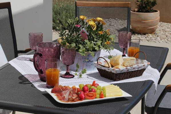 A table set with a fruit platter, bread, and drinks, surrounded by chairs and a potted plant. - Jezera Island Hideaway in Adriatic Sea (Tisno)