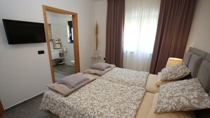 A bedroom with a bed, a TV, a mirror, a window with curtains, and a bedside lamp. - Jezera Island Hideaway in Adriatic Sea (Tisno)