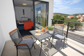 A balcony with a table set for breakfast, chairs, and a potted plant. - Jezera Island Hideaway in Adriatic Sea (Tisno)