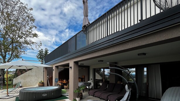 A modern outdoor living area with a pool, lounge chairs, and a covered seating area.